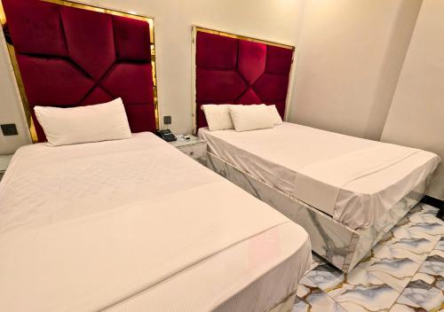 two beds in a room with red headboards at Dove Inn Hotel wahdat road in Lahore