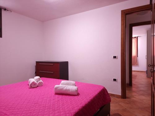 a bedroom with a pink bed with towels on it at Residenze Pedrame in Budoni