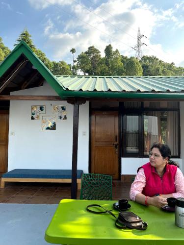 a woman sitting at a table in front of a house at Dolia Pahadi Myar Maiti in Rānīkhet