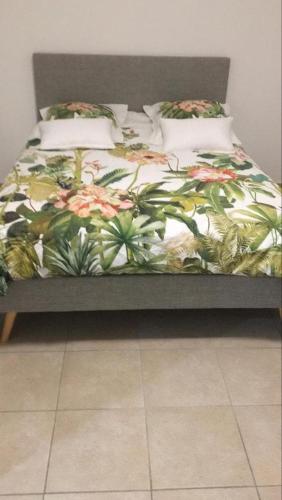 - un lit avec une couette et des oreillers à fleurs dans l'établissement Villa Pandoué - Peaceful oasis, à Cuers