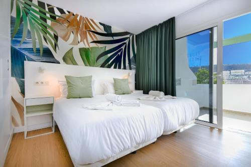 a white bed in a room with a large window at Palm Suites by Chaturhotels in Puerto Rico de Gran Canaria