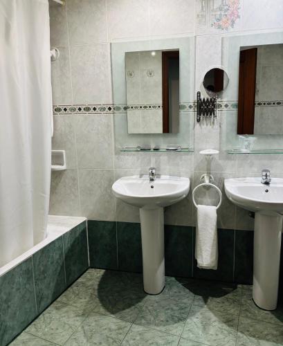 a bathroom with two sinks and a bath tub at Hotel Praderón in San Sebastián de los Reyes