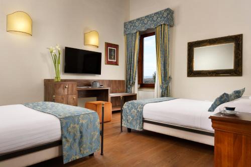 a hotel room with two beds and a television at Villa Sabolini in Colle Val D'Elsa