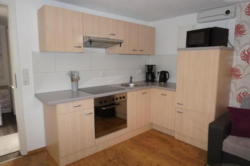 a small kitchen with wooden cabinets and a sink at Ferienwohnung Am alten Holzweg in Endlichhofen