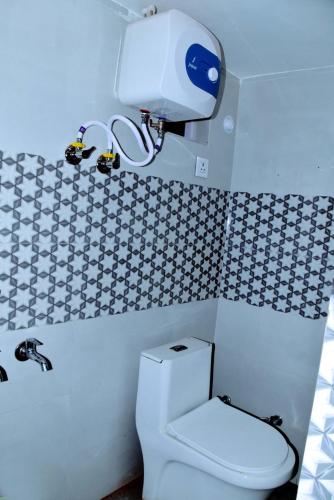a bathroom with a toilet and a hair dryer on the wall at The Ashoka Palace Near Ram Mandir in Ayodhya