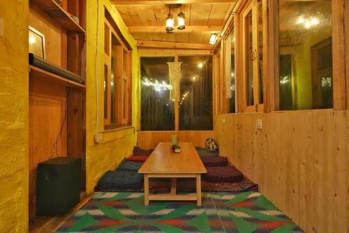 a room with a wooden table and a rug at Ailyak Stays Seri in Jibhi