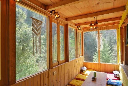 a room with large windows in a wooden house at Ailyak Stays Seri in Jibhi