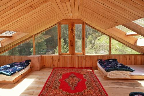 an attic room with two beds and a rug at Ailyak Stays Seri in Jibhi