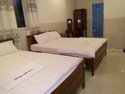 two beds with white sheets in a room at Kim Hồng Anh Guest House in Phu Quoc
