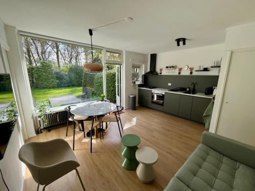 a kitchen and a living room with a table and chairs at Modern natuurhuisje midden in het bos op de Veluwe in Otterlo