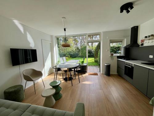 a kitchen and living room with a table and chairs at Modern natuurhuisje midden in het bos op de Veluwe in Otterlo