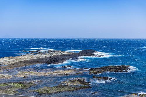 an island in the ocean with rocks and water at Ocean View Hiromi SPA Hotel温泉と絶景の宿 in Shimoda