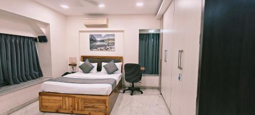 a bedroom with a bed and a chair and a window at TIM Service Apartment Goregaon East Near NESCO in Mumbai