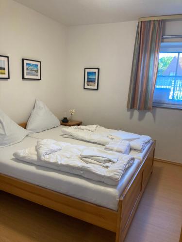 a bedroom with a bed with white sheets and a window at Sonnenstern Lemkenhafen in Fehmarn