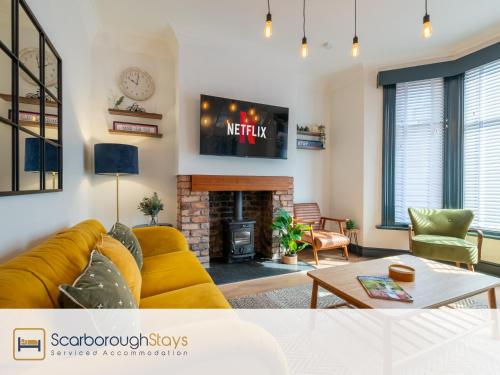 a living room with a yellow couch and a fireplace at Scarborough Stays - Darcey House in Scarborough