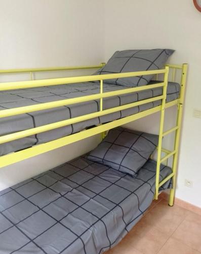 Ce lit superposé jaune se trouve dans un dortoir doté d'oreillers. dans l'établissement Appartement 2 chambres, piscines, jeux extérieurs, tennis, à Barbaste