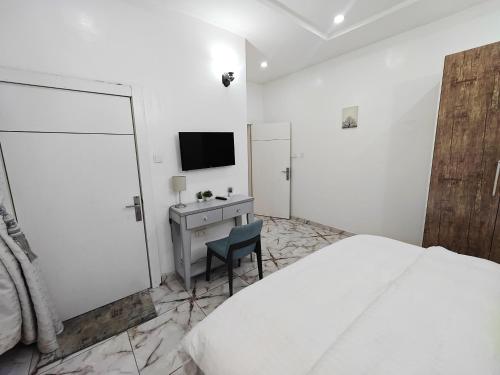 a bedroom with a bed and a desk and a television at Eko City Apartment - 24hrs Power, Security, Wifi, Netflix, Fully Equipped Kitchen in Lekki