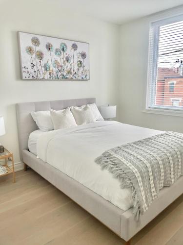 a white bedroom with a large bed with white sheets at Bright Luxurious 2 Bedroom Apartment in Toronto