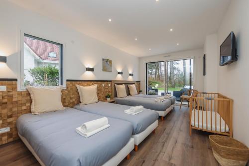 a bedroom with three beds and a television in it at La Villa Léo face au Centre Equestre et Piscine in Neufchâtel-Hardelot