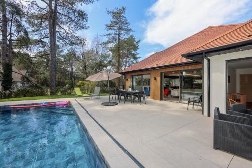 une terrasse avec une piscine et une maison dans l'établissement La Villa Léo face au Centre Equestre et Piscine, à Neufchâtel-Hardelot