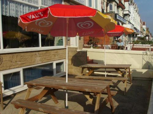 two picnic tables with a cocacola umbrella on a sidewalk at Dora Hotel in Blackpool