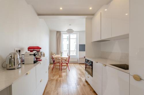 une cuisine avec des armoires blanches et un plancher en bois dans l'établissement Cozy Faubourg St Martin retreat, à Paris
