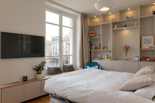 une chambre avec un grand lit et une grande fenêtre dans l'établissement Cozy Faubourg St Martin retreat, à Paris
