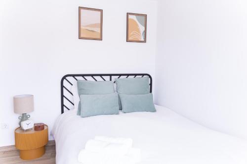 a white bedroom with a bed with blue pillows at Casa Alagoa in Montemor-o-Velho