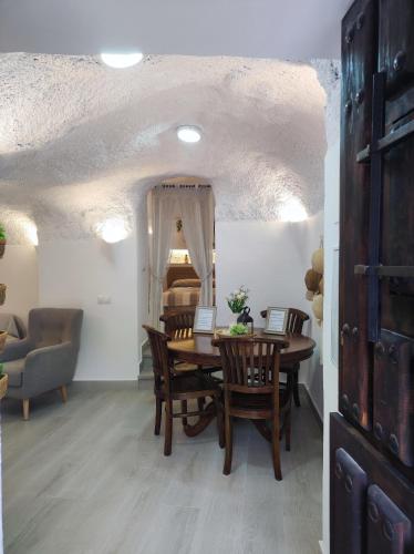 a dining room with a table and chairs and a bedroom at Cueva Virgen de las Nieves in Monachil