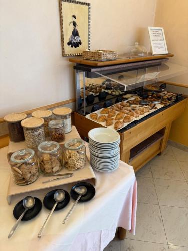 a table with bowls and spoons and some pastries at Hotel Fortuna in Chioggia