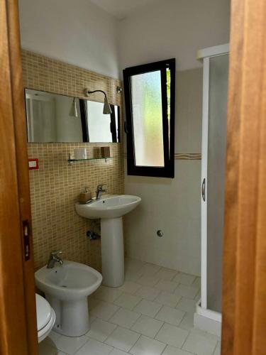 a bathroom with a sink and a toilet and a mirror at L'Asfodelo in Uggiano la Chiesa