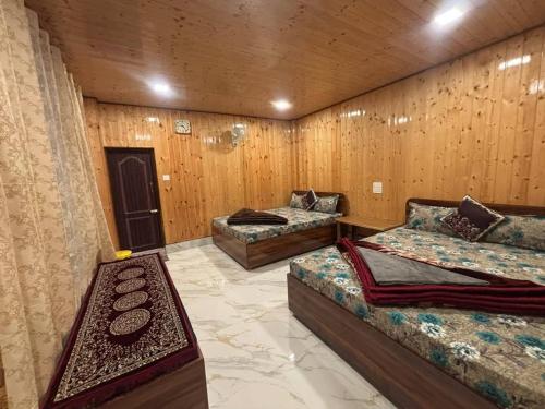 two beds in a room with wooden walls at Rehan Homestay in Pedong