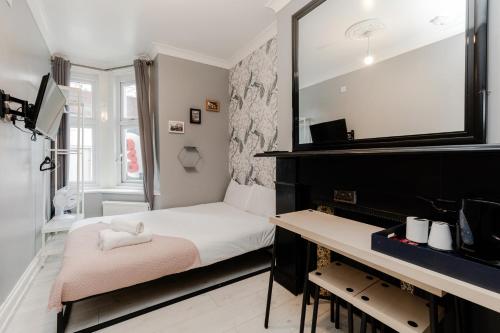a small bedroom with a piano and a mirror at Orlando hotel in London