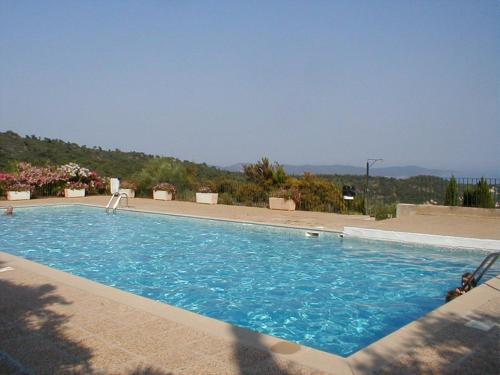 une grande piscine bleue avec des montagnes en arrière-plan dans l'établissement joli studio rez de jardin résidence avec piscine, à Cavalaire-sur-Mer