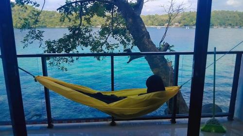 a person sitting in a hammock overlooking the water at Diara Bungalow in Iboih