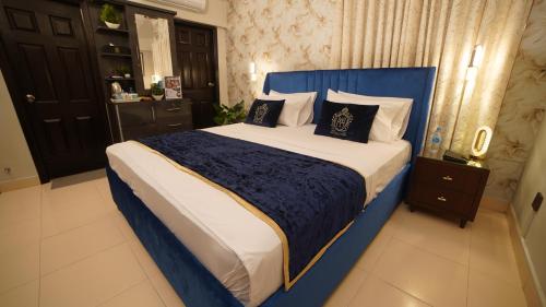 a bedroom with a blue and white bed with pillows at Service Apartment by World Inn in Karachi