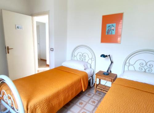 a bedroom with two beds and a lamp on a table at Eco House San Michele in San Michele