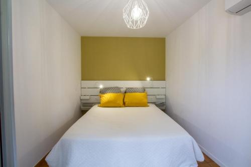 une chambre avec un lit blanc avec des oreillers jaunes dans l'établissement Bri'gite, à Sarlat-la-Canéda