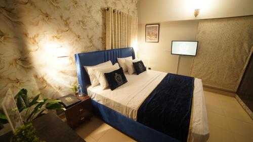 a bedroom with a blue bed with pillows on it at Service Apartment by World Inn in Karachi