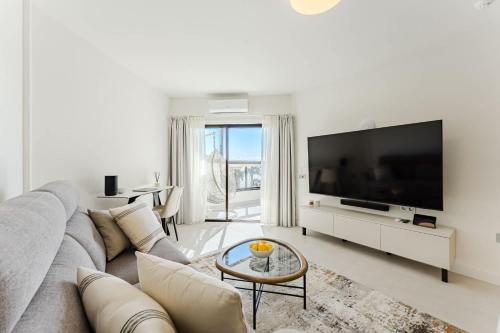 a living room with a gray couch and a flat screen tv at Atlantic View Premium Oceanfront Suite in Costa Del Silencio