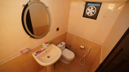 a bathroom with a sink and a mirror and a toilet at Service Apartment by World Inn in Karachi