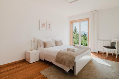 una camera da letto bianca con un letto e una finestra di Casa Do Golf Ponte de Lima a Ponte de Lima