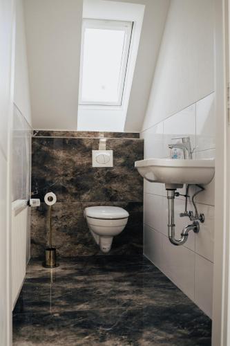 a bathroom with a toilet and a sink and a window at Ella am See, Ferienhaus in Fintel