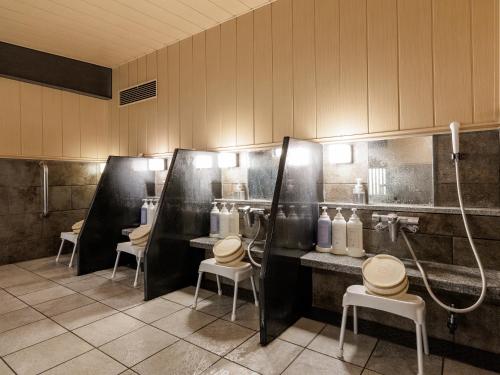 a bathroom with three stalls with toilets and a shower at Nishitetsu Inn Kurosaki in Kitakyushu