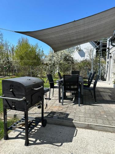 a grill and a table and chairs under a canopy at Verandás Vendégház in Balatonkenese