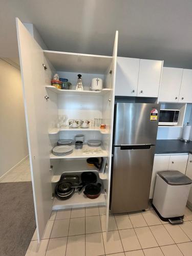 a kitchen with a stainless steel refrigerator and white cabinets at Unbeatable location with FREE parking-Limited offer in Auckland