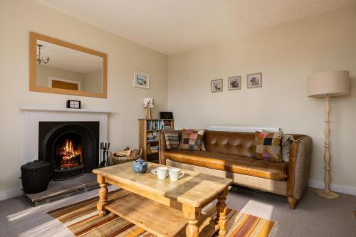 een woonkamer met een bank en een open haard bij Kirktoun Cottage in Duffus