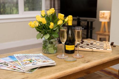 een tafel met een vaas van gele bloemen en wijnglazen bij Kirktoun Cottage in Duffus