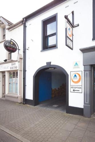 a white building with a blue door on a street at Bushmills Hostel in Bushmills