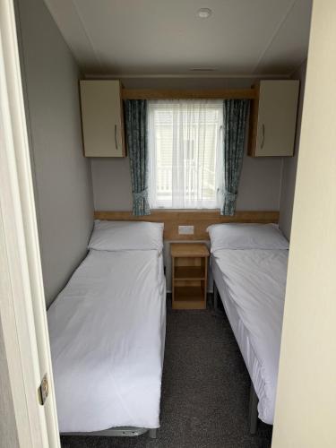 two beds in a small room with a window at Glenlea in Selsey